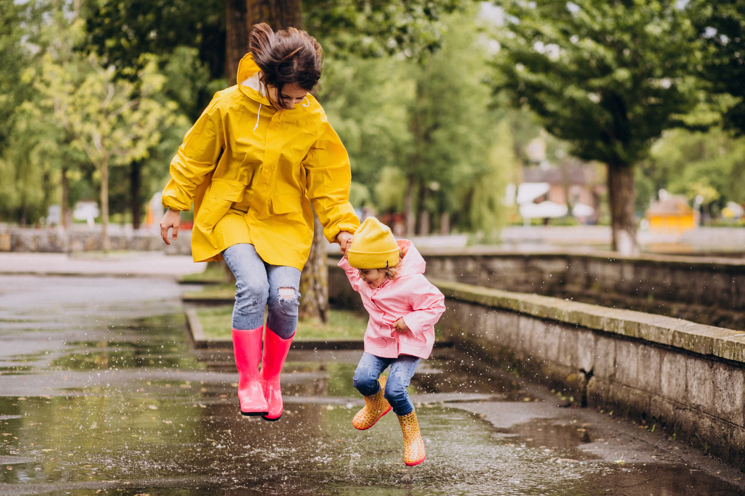 mother with daughter having fun jumping puddles